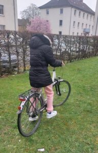 Mädchen testet ein vom WFK e.V. gespendetes Fahrrad auf einer Wiese aus